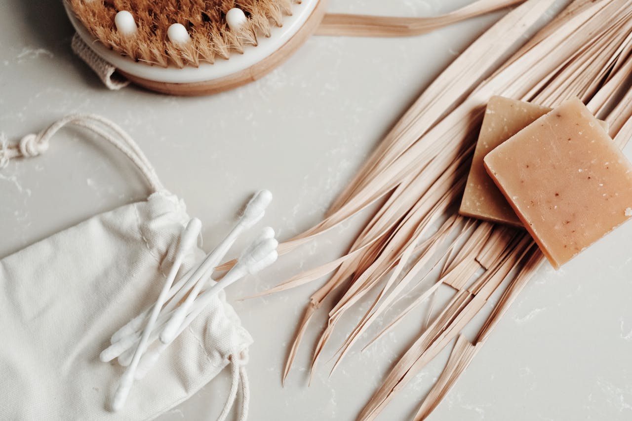 Aesthetic flat lay of natural body care items including soap, dry brush, and cotton swabs promoting a sustainable lifestyle.